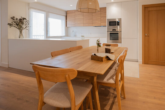 Modern apartment dining area with wooden table and kitchen