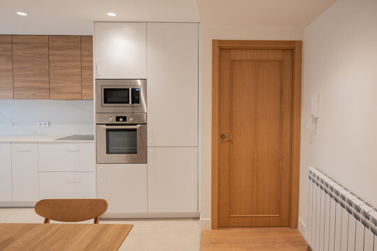 Modern apartment kitchen with wooden door and dining table