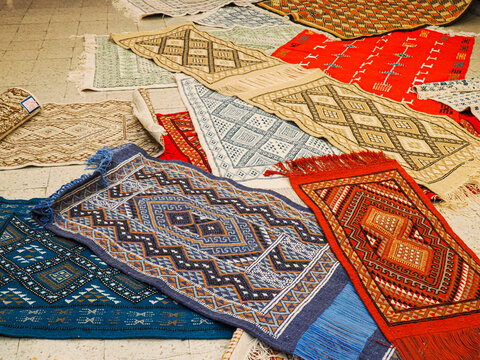 Pile of colorful handmade woolen rugs presented in traditional suq market in north african islamic Tunisia. 