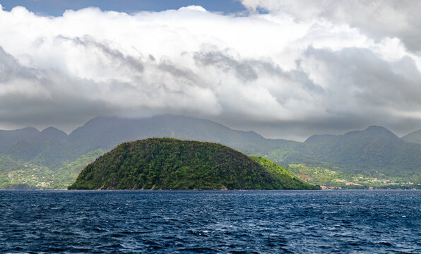 Beautiful tropical landscape of the island of Dominica featuring the Cabrits Peninsula and lush green mountains with a calm blue sea in the foreground.