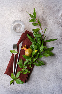 Autumnal pomegranate table set with leafy branch and cutlery
