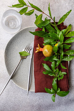 Autumnal pomegranate table set with leaf branch and cutlery