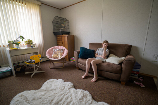Girl sitting alone on sofa in a quiet bedroom
