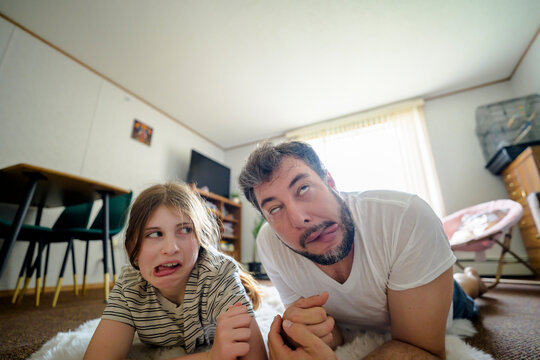 Father and daughter make funny faces on living room floor