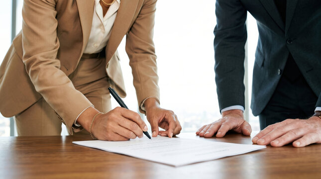 Close view of hands signing a document at a boardroom table