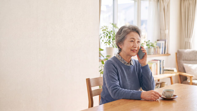 自宅でスマートフォンの通話を楽しむシニア女性