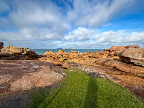 Pink granite boulders scattered along sandy shore in Tregastel, France
