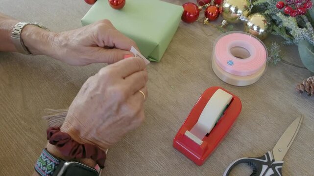 Woman's hands tying a christmas gift tag