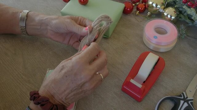 Woman preparing twine for christmas gift wrapping