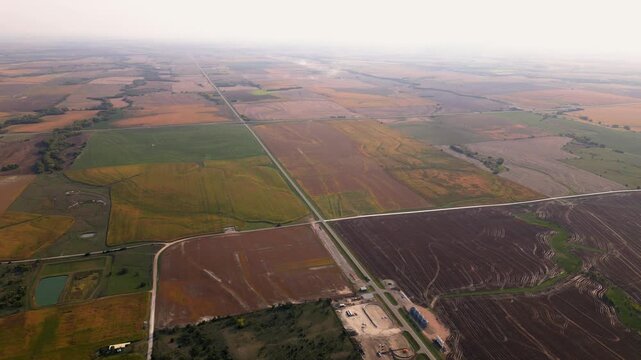Very high aerial over patchwork farmland and a straight highway