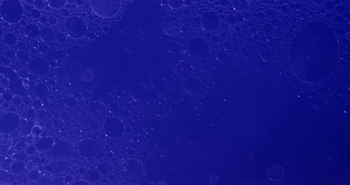 Soft abstract beauty background with delicate oil bubbles floating in clear liquid, illuminated by multicolored light to create a clean cosmetic texture.