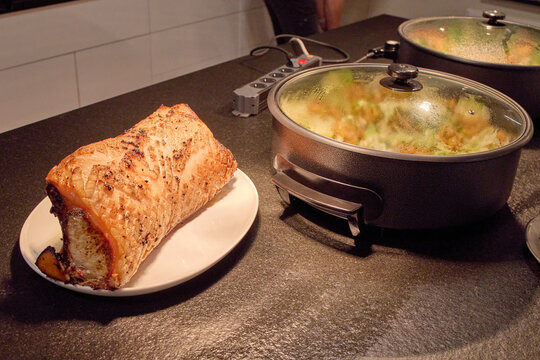 Roasted meat loaf with crispy crust on a plate next to electric buffet pans at a catering station.