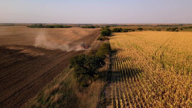 Aerial of dust rising behind a tractor on a harvested field