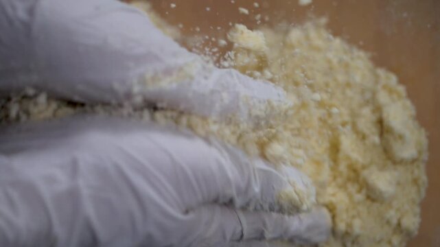 White gloves work flour and butter for sweet pie. Crumb formation marks readiness. Essential phase in making soft, buttery pastry base