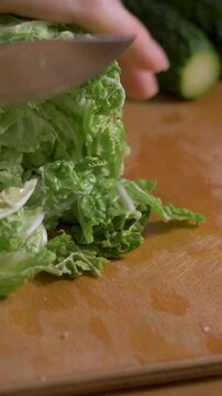 Mother hands cut lettuce leaves on board by knife. Fresh salad from green leaf vegetable brings vitality and calm mood 