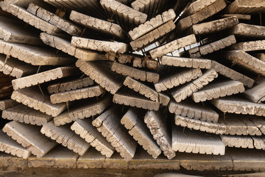 Full frame geometric pattern of stacked weathered timber boards. Chaos texture of old beach boardwalk planks.