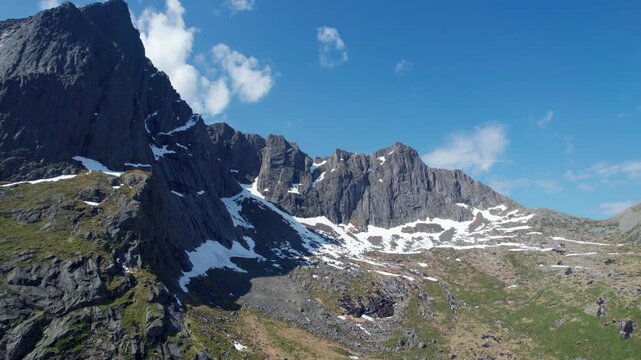 Majestic aerial view of a rugged mountain range with lingering snow patches in the Lofoten islands of Norway under a clear blue sky