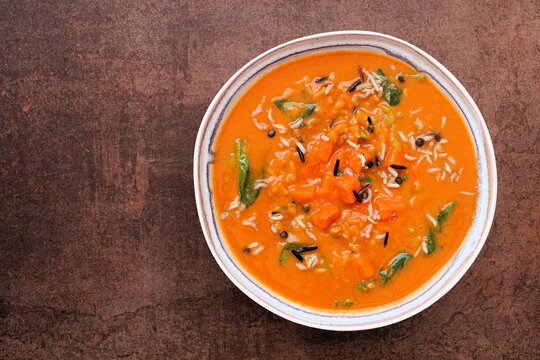 Autumn sweet potato soup with wild rice, warm spices and herbs. Top view on a dark background.