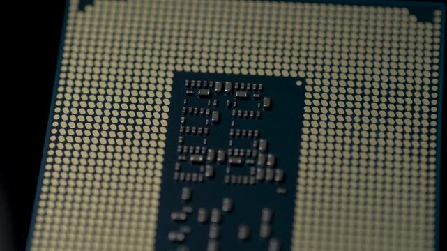 Hightech microprocessor bottom surface with gold pads and miniature capacitors. Contact layout supports reliable motherboard connection and precise installation via corner marker