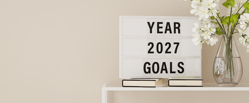 A lightbox displaying the words "Year 2027 Goals" on a shelf with books and plants. Copy space, web banner format.
