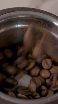 Grinder stands on kitchen table, pours roasted beans inside. Coffee aroma fills space. Concept of energy for active start and clear focus