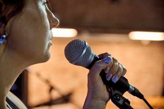 Female singer holding microphone during band sound check on warm stage