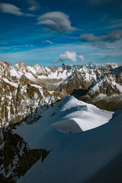 Aerial view of Mont Blanc massif with snow-covered peaks, dramatic shadows, and a clear blue sky in Chamonix, Auvergne-Rhone-Alpes, France.