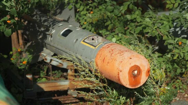 Obsolete, abandoned, and rusty combat missiles and shells stand amidst the natural landscape. A weapons graveyard. An echo of war.