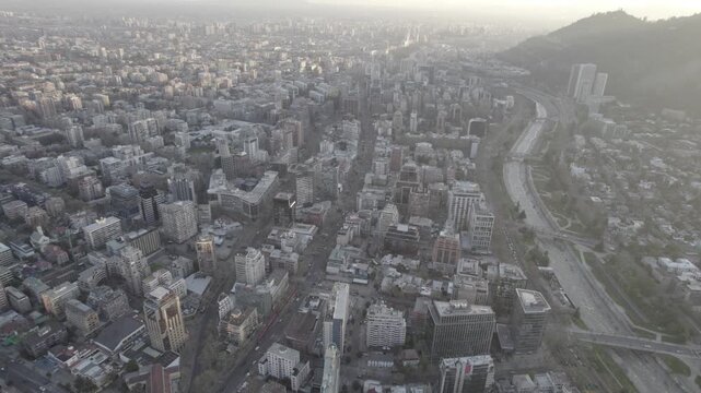 Aerial Drone Pan Shot Over Providencia Skyline And Mapocho River At Sunset, Santiago de Chile
