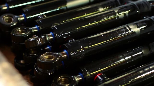 Worker hands sorting oiled shock absorber rods. Closeup metal parts factory.