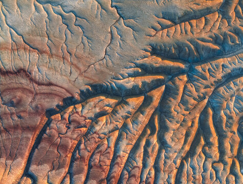 Aerial view of intricate geological erosion patterns and colorful sedimentary layers in the desert landscape of Mangistau, Mangystau Region, Kazakhstan.