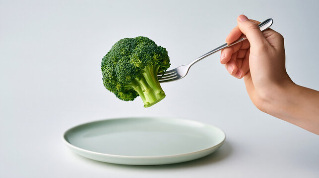 Woman holding broccoli on fork above pla 3