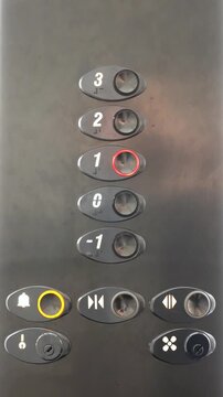 Hand pressing the first floor button in a modern elevator, close-up of lift control panel and floor selection
