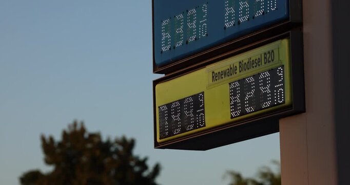 High gas prices display on a board at a gas station on a city street.