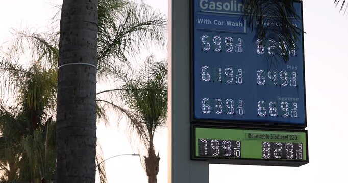 High gas prices display on a board at a gas station on a city street.