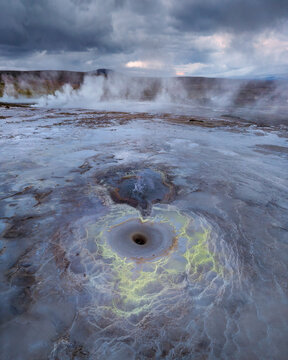 Aerial view of a steaming geothermal vent with vibrant yellow mineral deposits in the volcanic landscape of the Icelandic Highlands, Iceland.