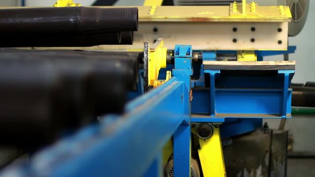 Metal pipe production line factory. Closeup conveyor rollers moving steel tubes.
