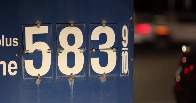 High gas prices display on a board at a gas station on a city street.