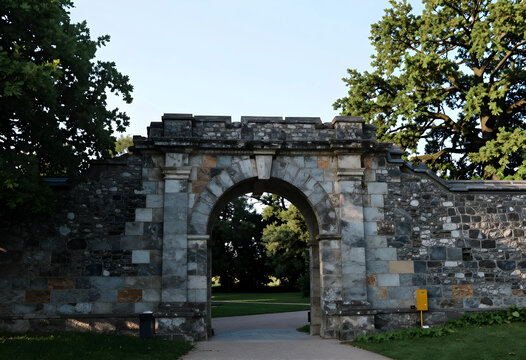 Heritage preservation and historical architecture, ancient stone archway entrance in a public park with lush green trees and garden landscape scenery