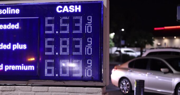 High gas prices display on a board at a gas station on a city street.