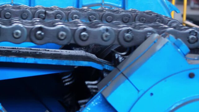 Chain sprocket closeup blue industrial machine. Factory conveyor gear drive.