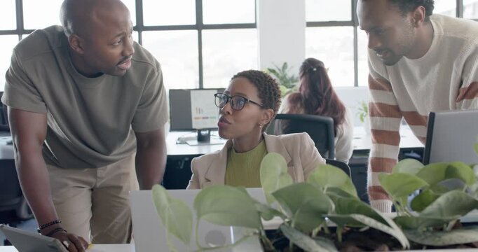 African American coworkers leaning over desk, discussing monitor, sparking questions, laughing