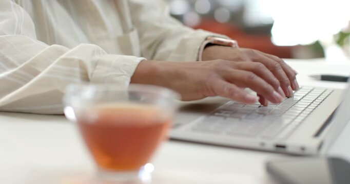 Hands are starting to press keys, typing on silver laptop at white desk while working