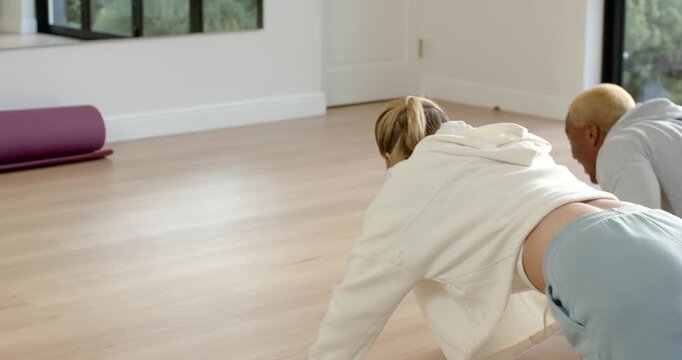 Diverse exercise partners starting synchronized push-up set at home studio, checking form in mirror