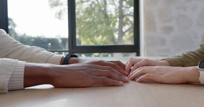 Left hand is reaching, causing fingers to interlock and clasp for comfort on table near window