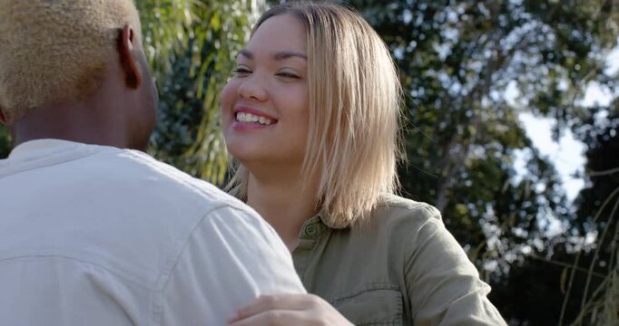 Couple exchanging smiles, holding hands, hugging in garden, showing love, ring and watch