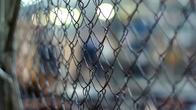 Chain link fence close up industrial workshop. Rack focus blurred plant worker.