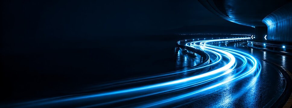 Futuristic light trails on a wet highway curve at night, representing high speed, modern transportation, and technology connectivity in an urban environment.