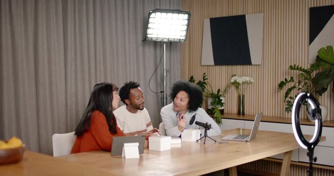 African American creators picking gadget from white box, passing to mic for demo at studio