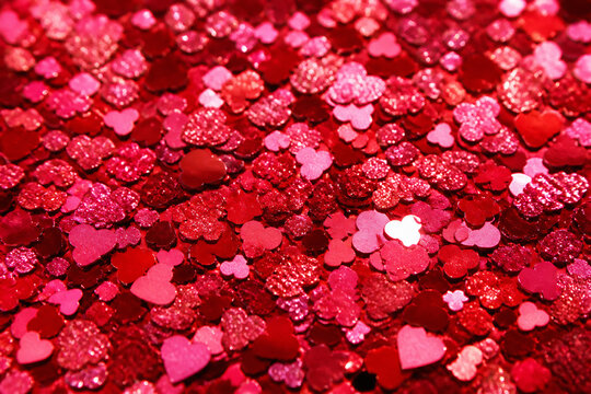 A close-up texture of vibrant red and pink heart-shaped sequins covering a surface.